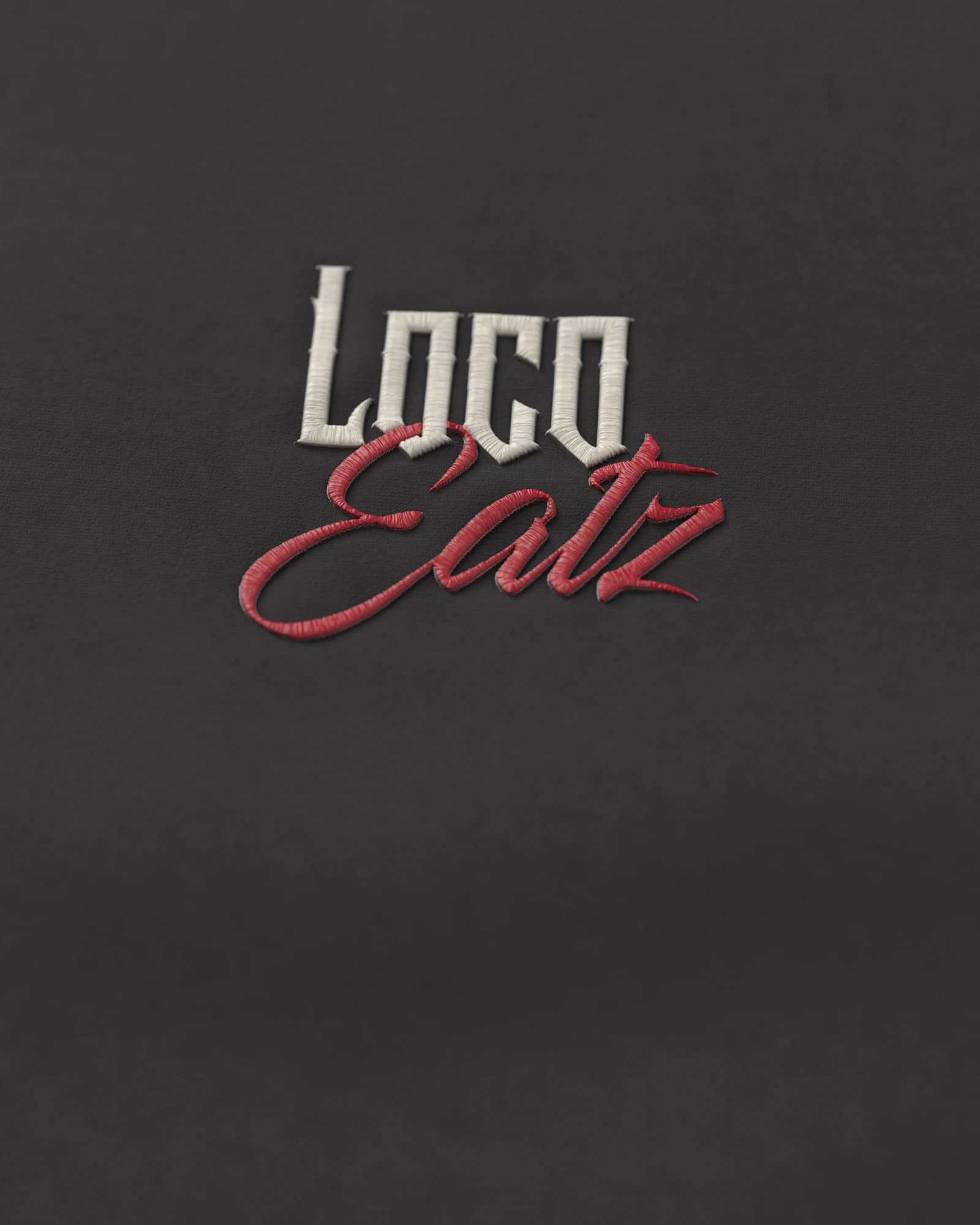 The Loco Eatz wordmark embroidered in raised satin stitch on the Signature Hoodie’s black fleece