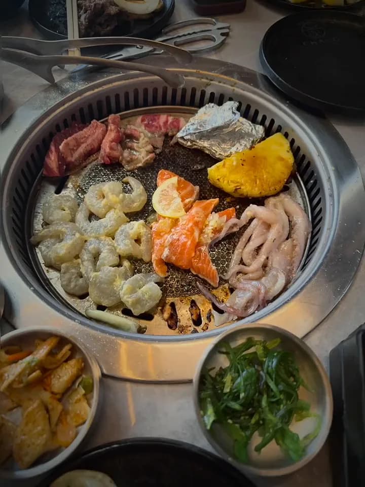A Korean barbecue grill with shrimp, salmon, squid and pineapple