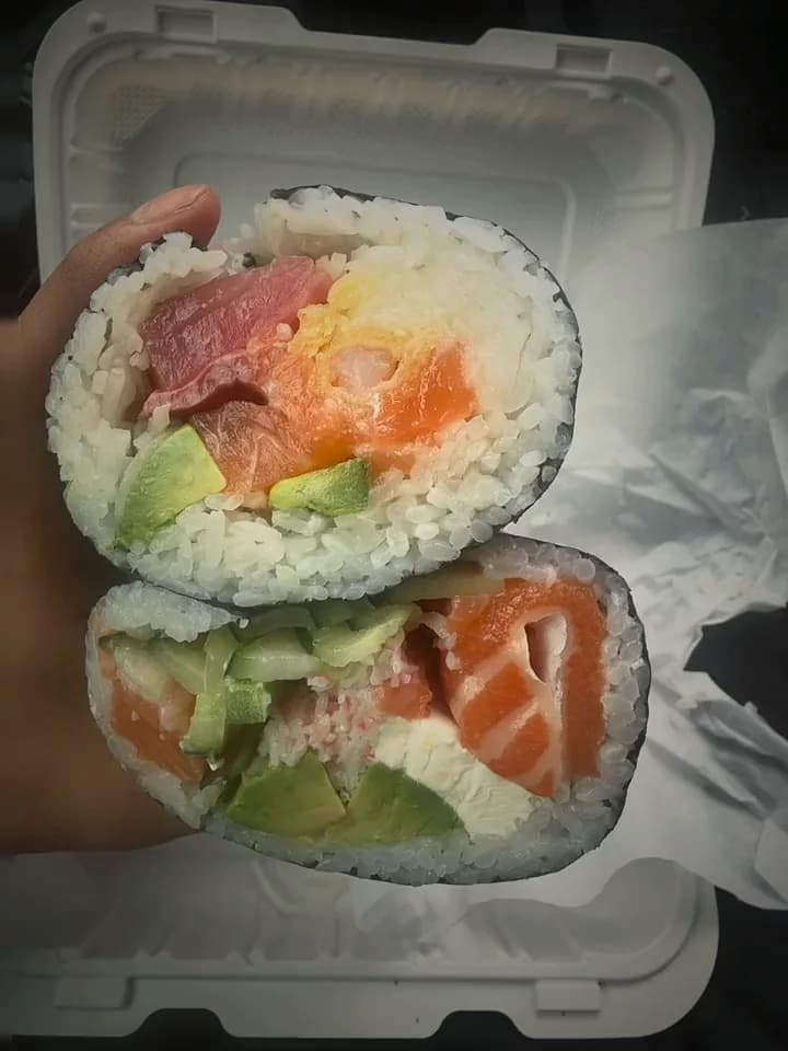 A sushi burrito cut in half, showing tuna, salmon and avocado