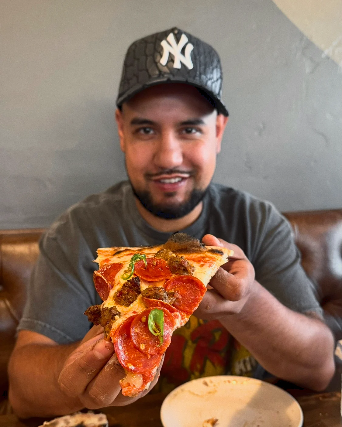 Brandon holding a pepperoni and sausage pizza slice out toward the camera