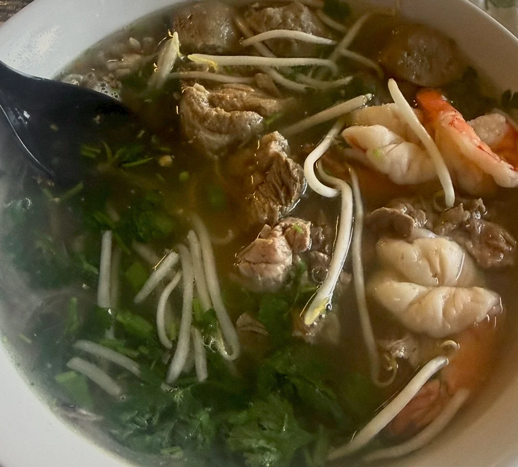 A bowl of pho with beef, meatballs, shrimp, bean sprouts and fresh herbs